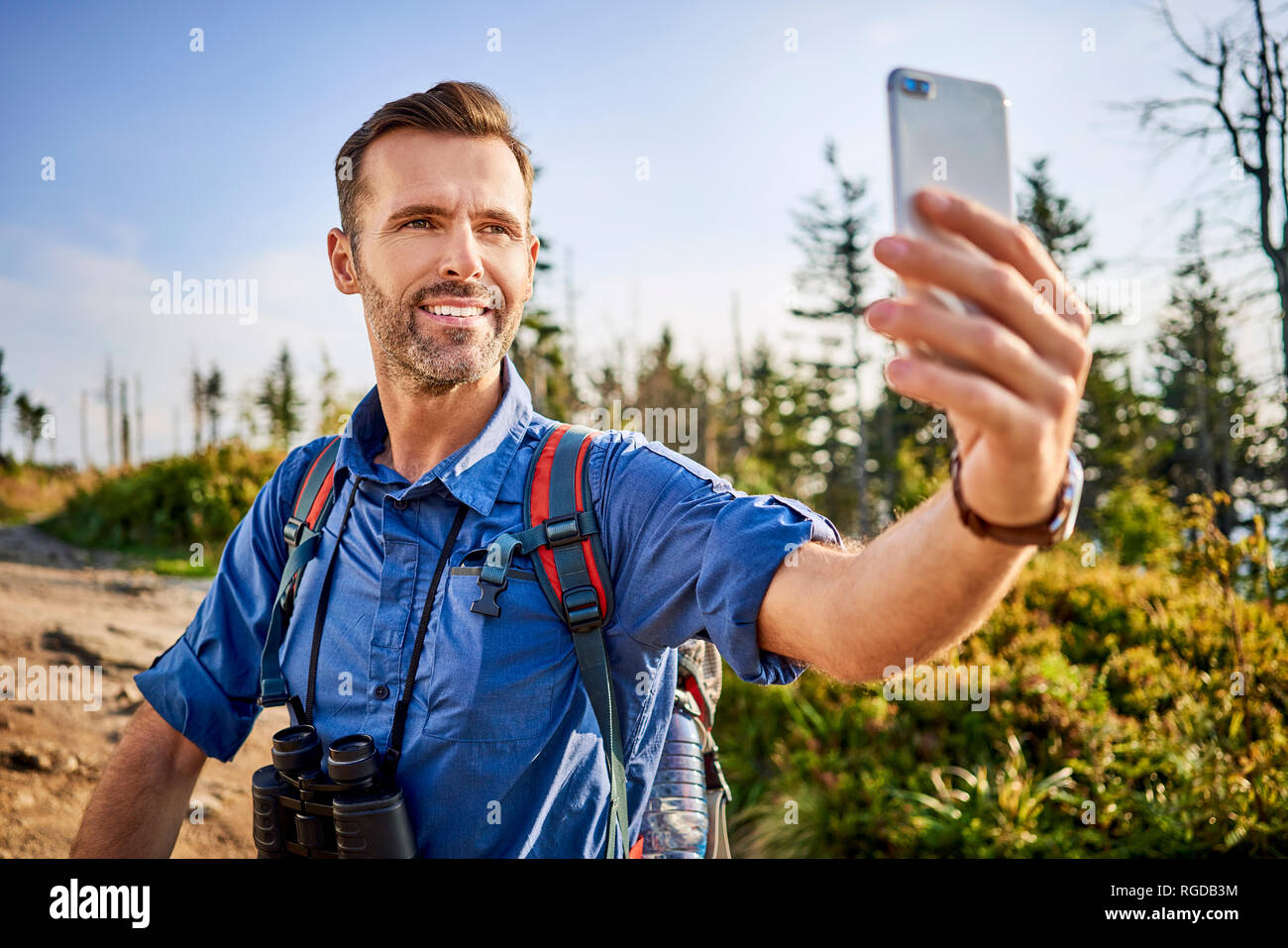 Man taking a selfie with his cell phone during hiking trip in the mountains Stock Photo