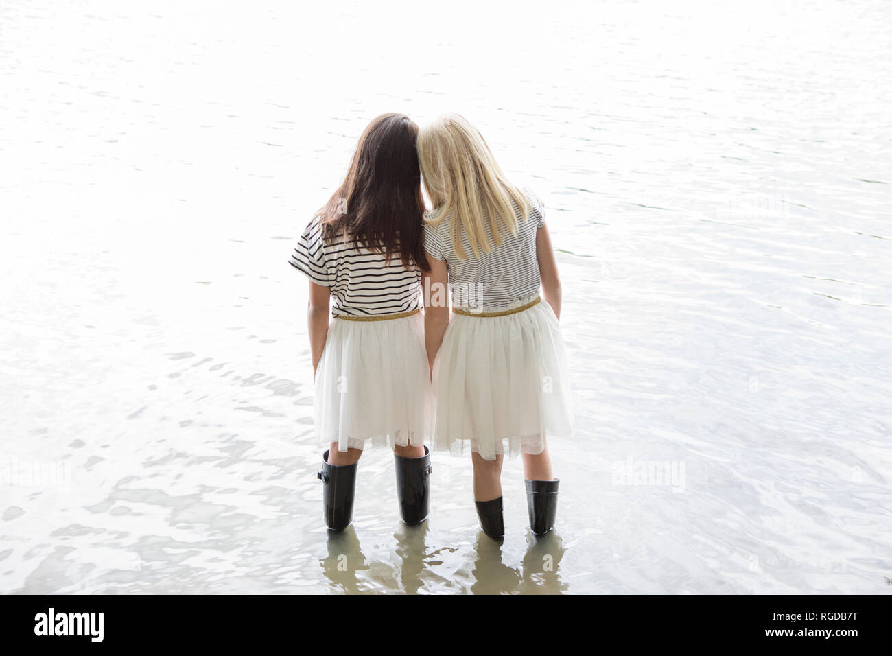 Back view of two best friends standing head to head in a lake Stock Photo