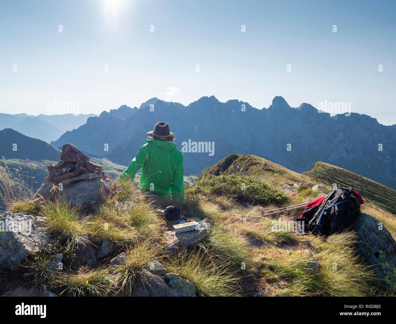 Italy, Lombardy, Bergamasque Prealps, hiker sitting on viewpoint of Monte Gardena, Cima Bagozza against the sun Stock Photo