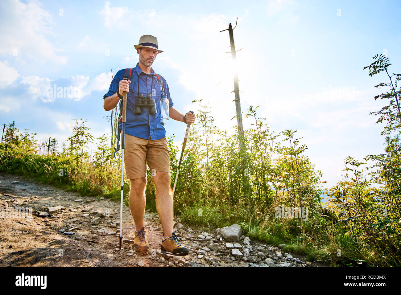 Man walking carefully with hiking poles on trail Stock Photo