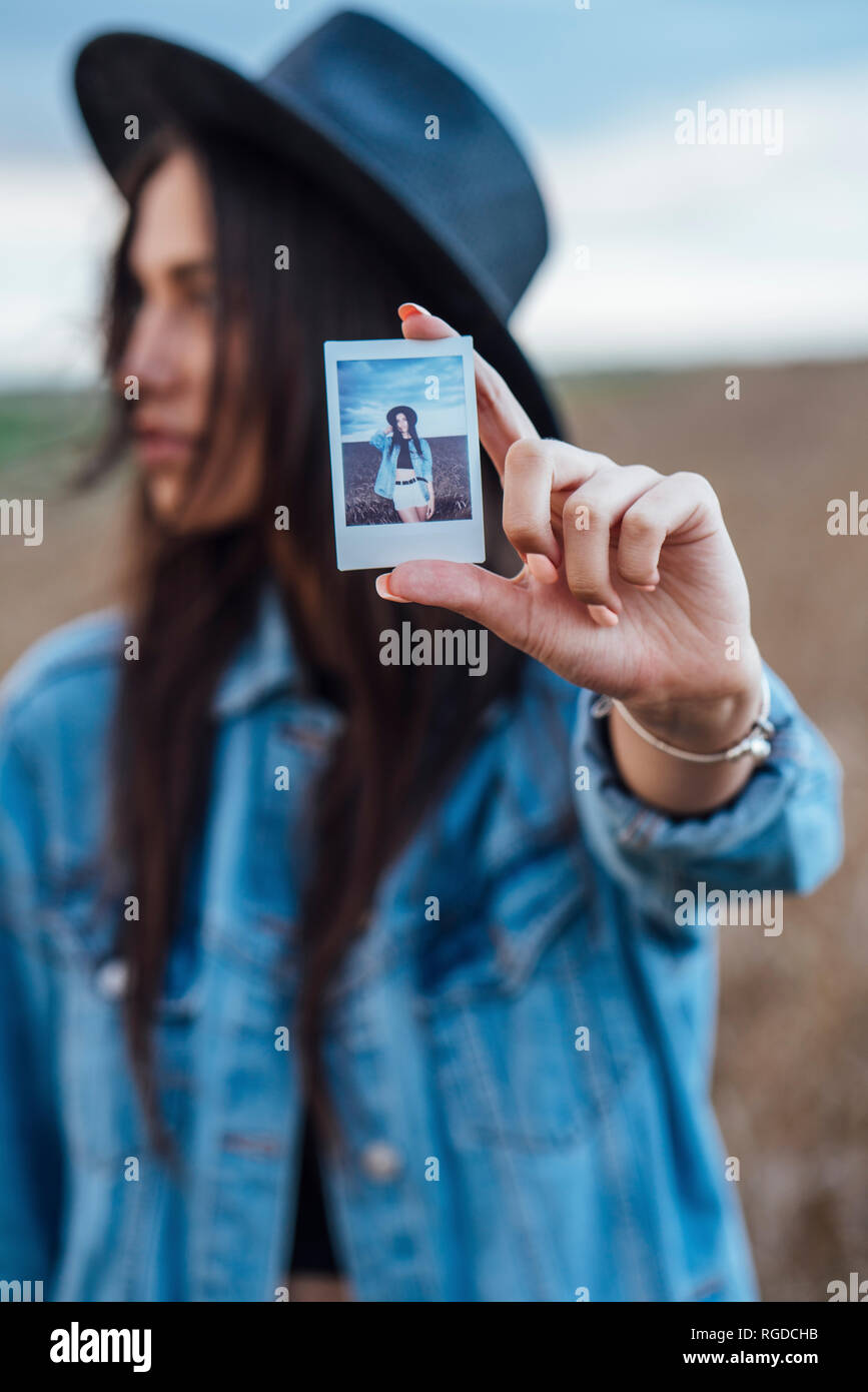 Young woman showing instant photo of herself, close-up Stock Photo