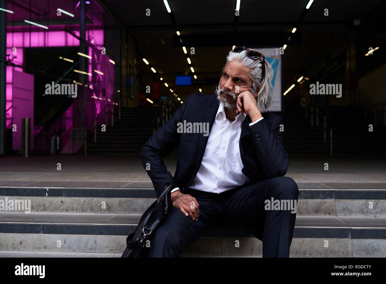 Stylish senior businessman sitting on stairs outdoors Stock Photo