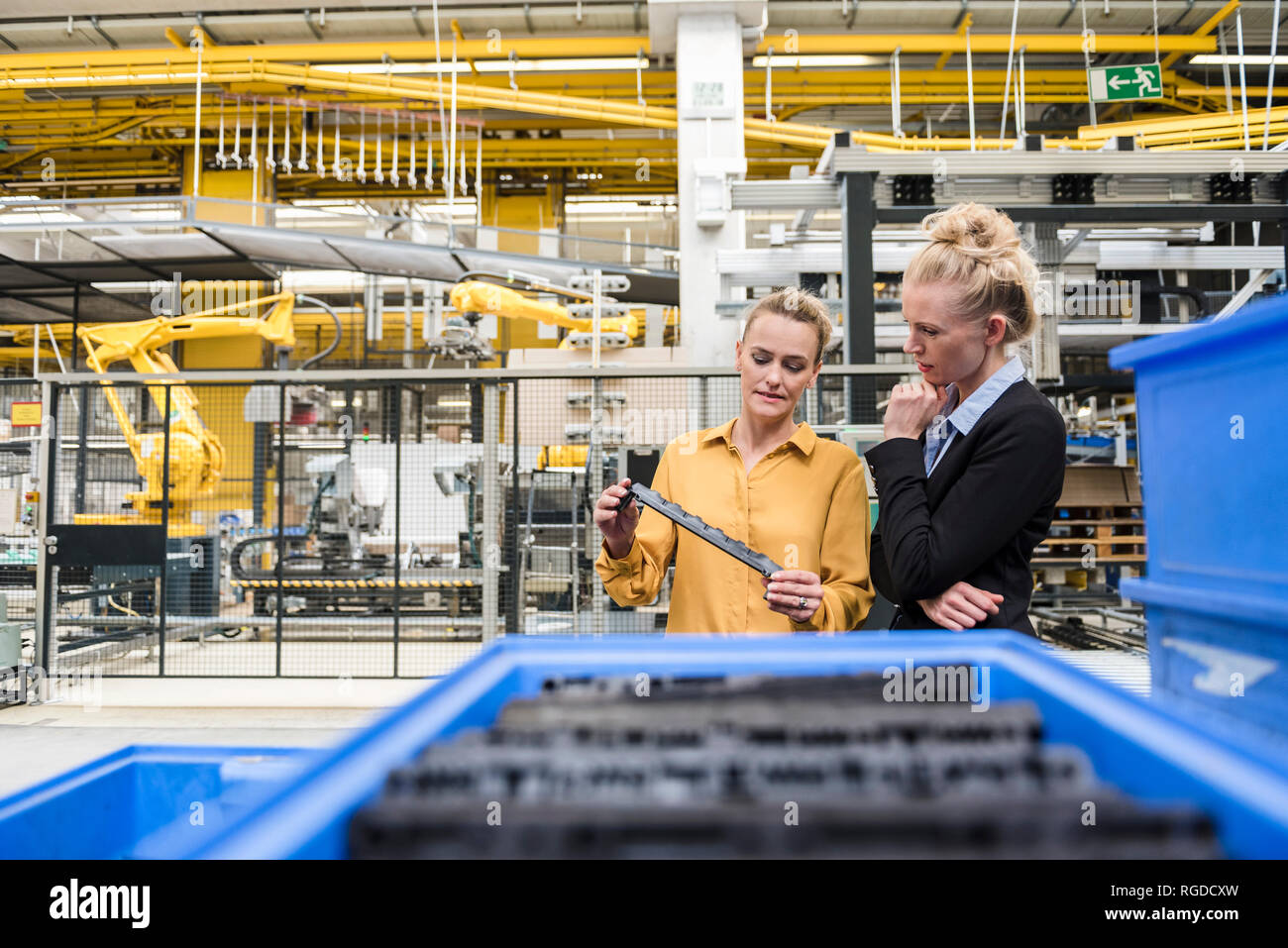 Two women examining workpiece in factory Stock Photo