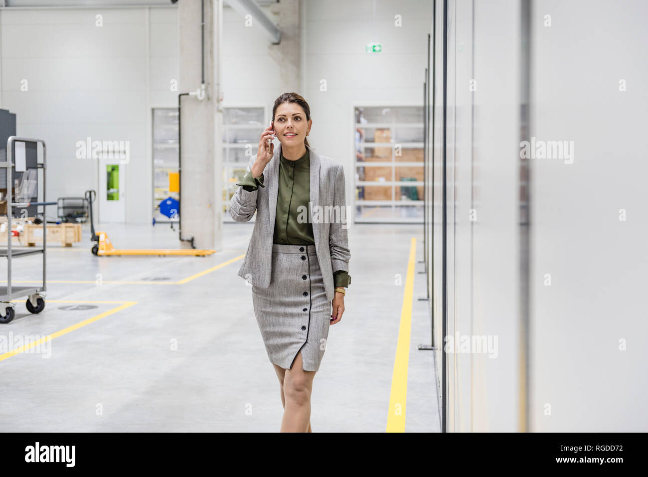 Businesswoman walking in factory workshop, talking on the phone Stock Photo