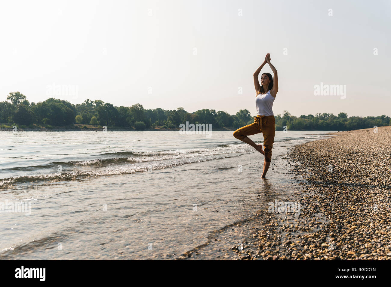 Young woman standing in water of a river practicing yoga Stock Photo