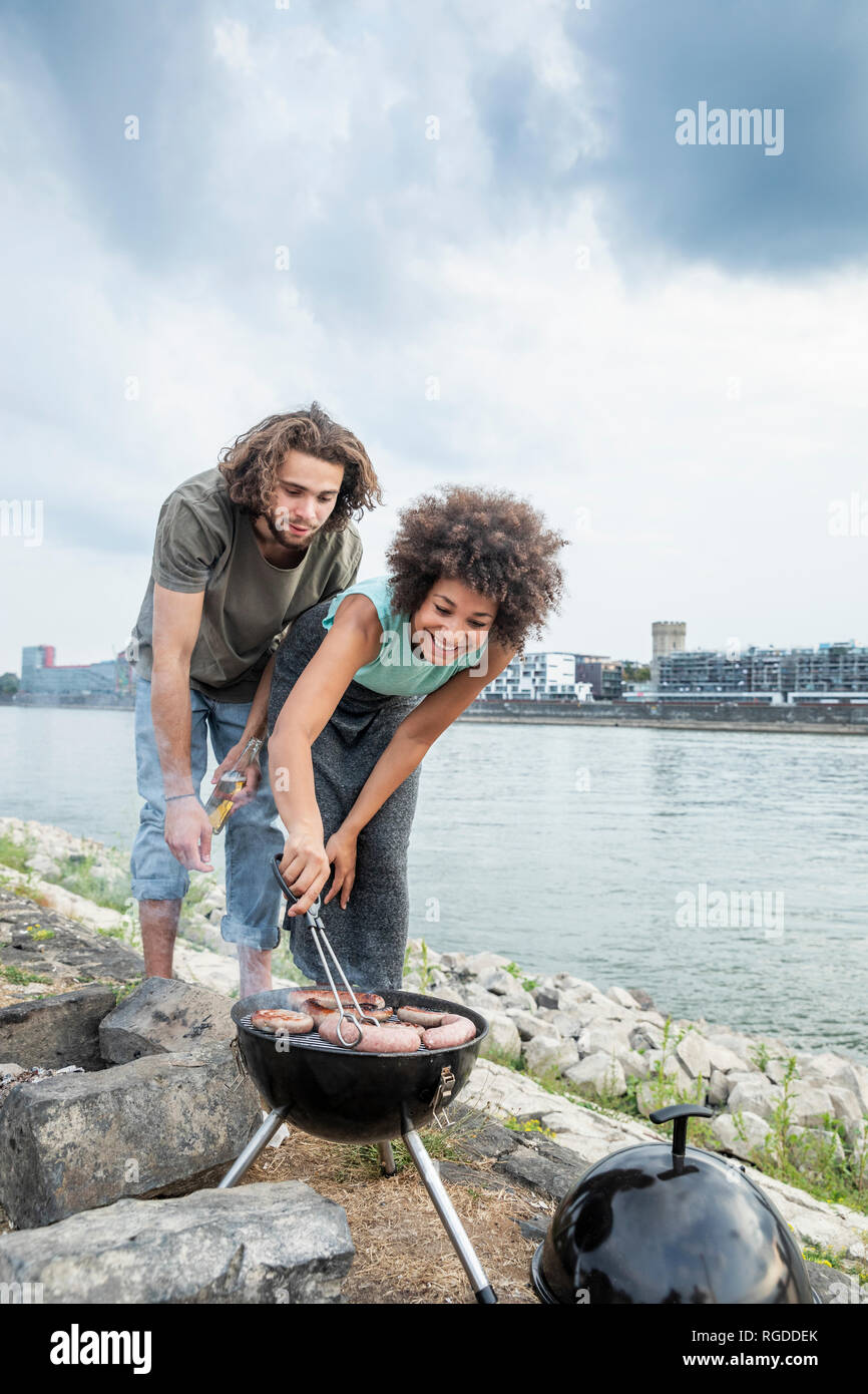 Germany, Cologne, couple having a barbecue at the riverside Stock Photo