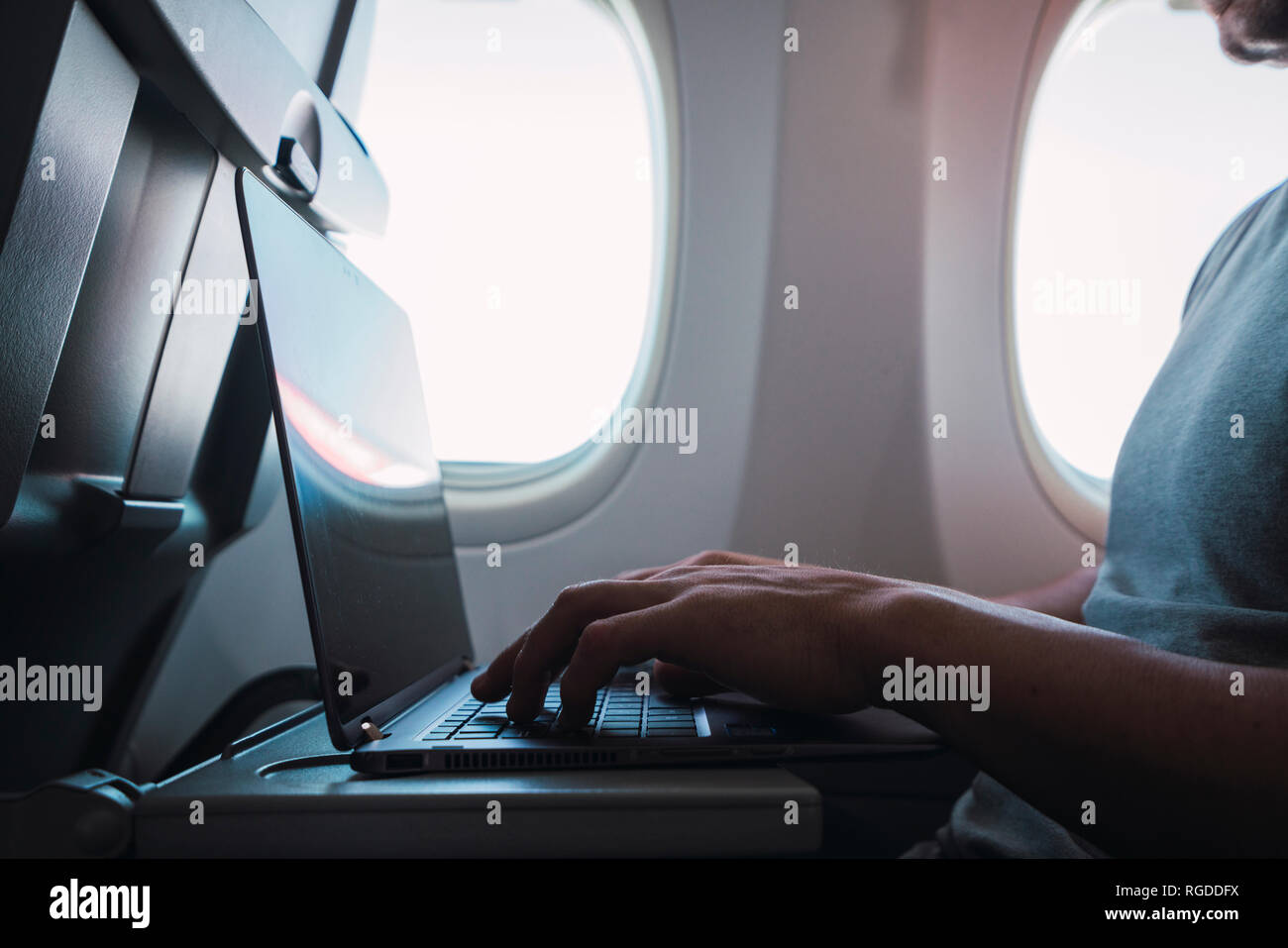 Man using laptop in airplane Stock Photo