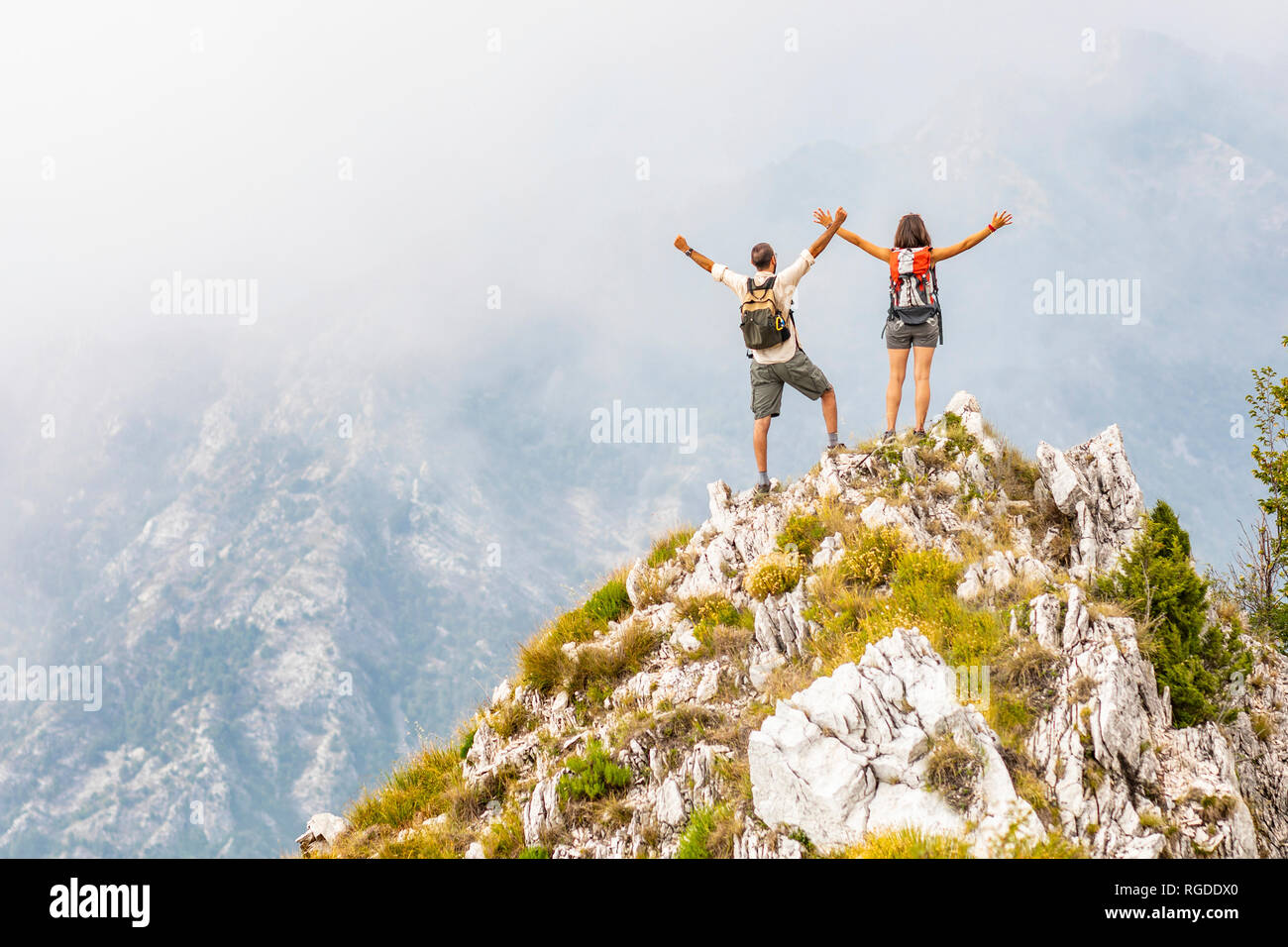 Italy, Massa, happy couple cheering on top of a peak in the Alpi Apuane mountains Stock Photo