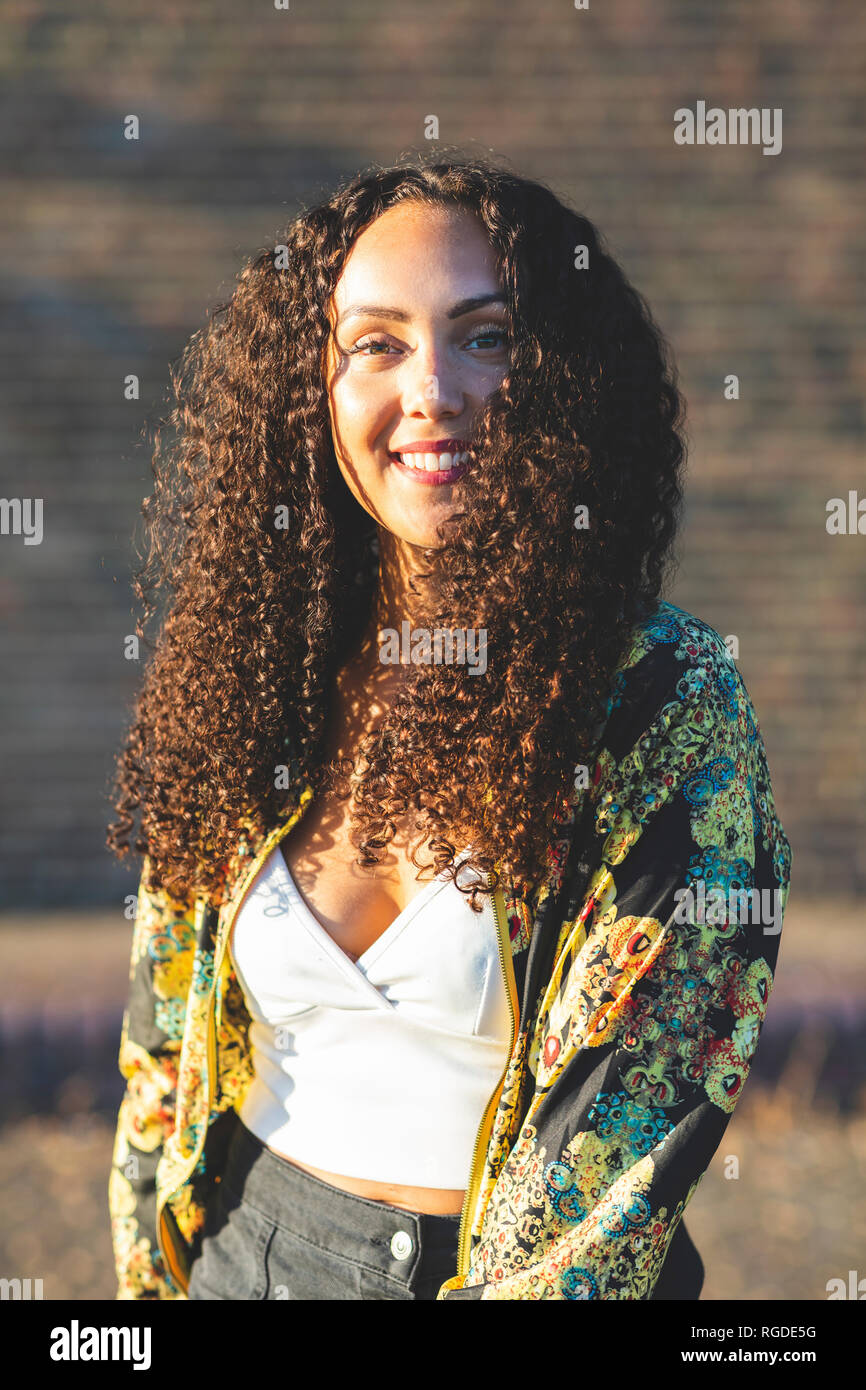 Portrait of smiling young woman with curly hair outdoors Stock Photo ...