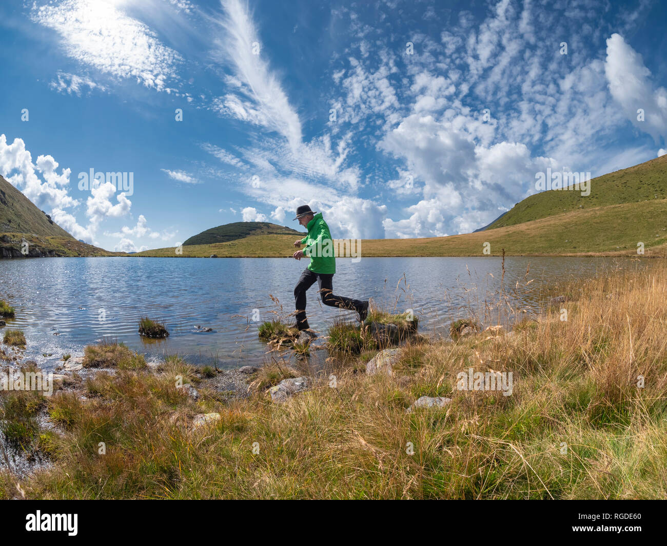 Italy, Lombardy, hiker jumping at lakeside Stock Photo