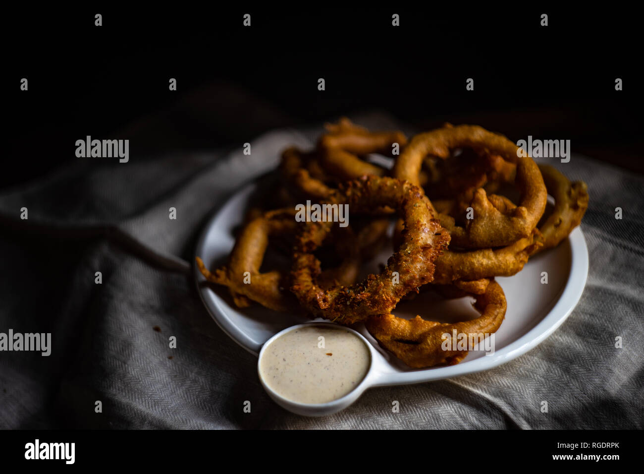Golden onion rings on rustic table with sauce Stock Photo - Alamy