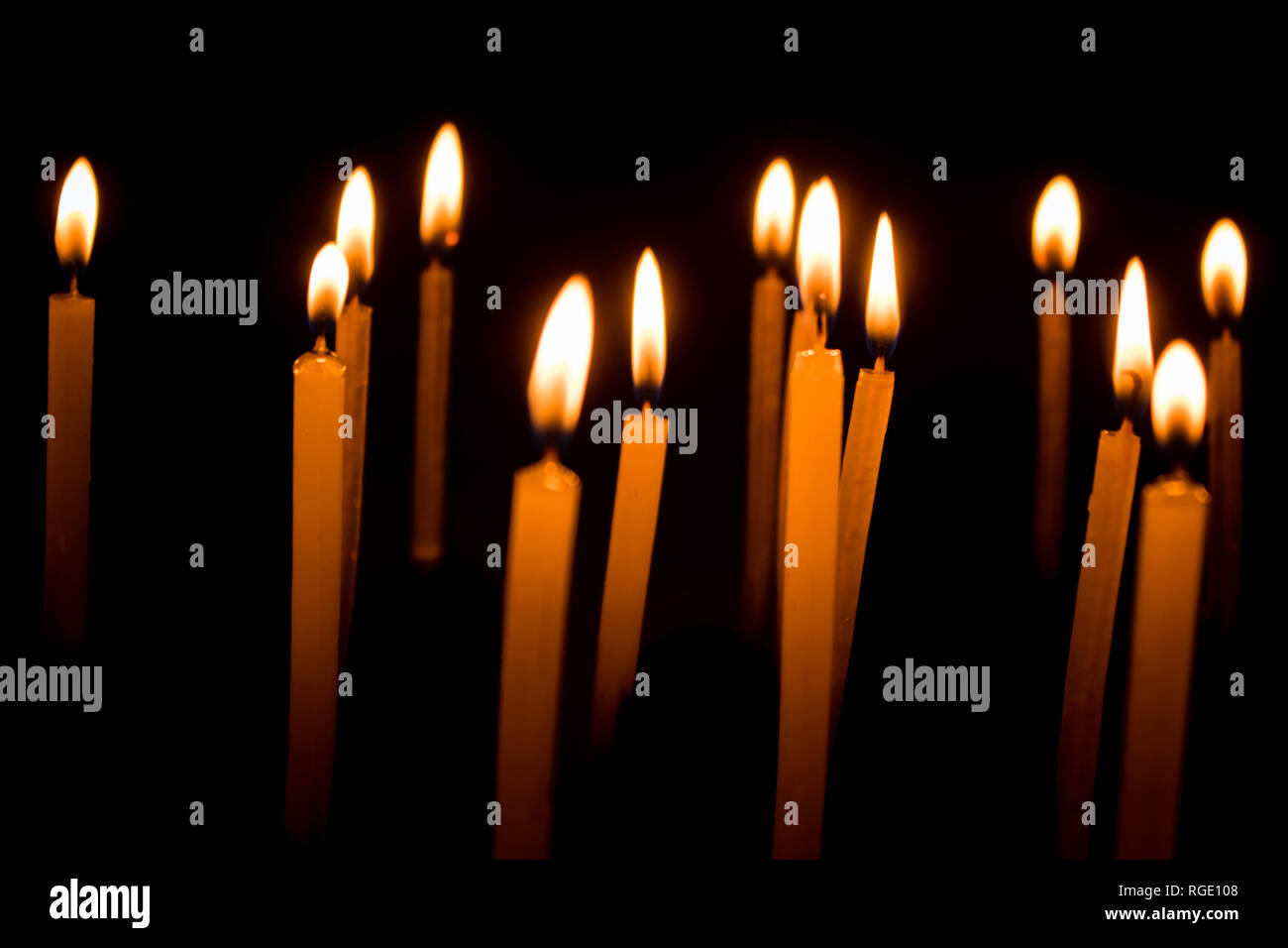 Many christmas candles burning at night on the black background. Candle flame set isolated in black background. Group of burning candles in dark with Stock Photo