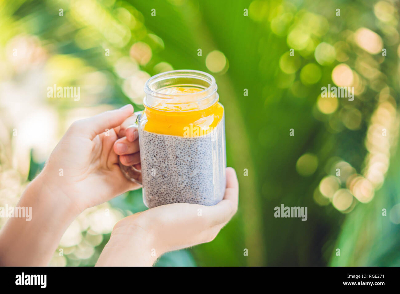 Chia seed pudding with almond milk and fresh mango topping in hand