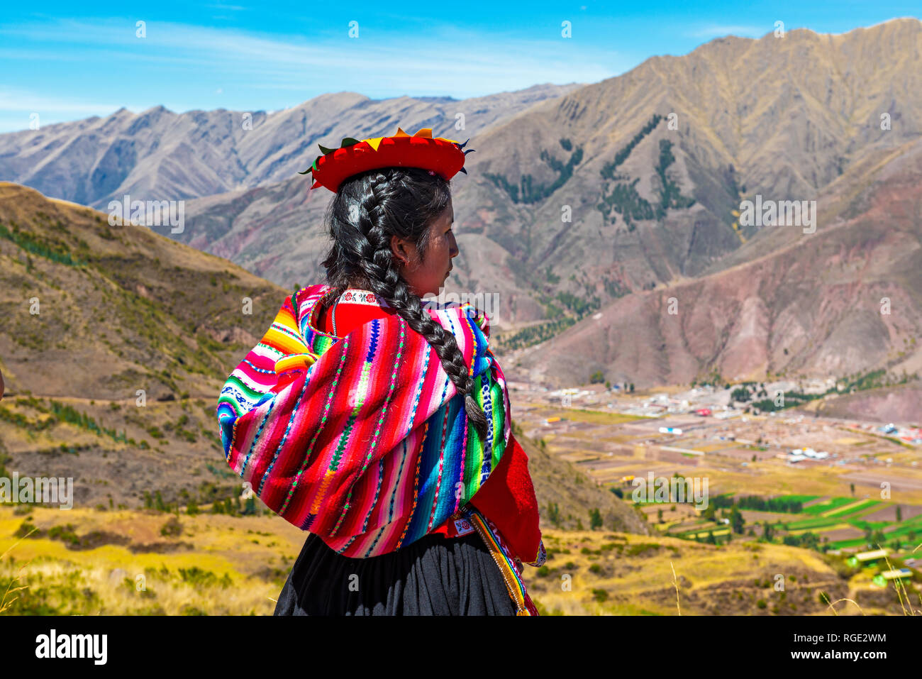 Young Quechua indigenous woman in traditional clothing by the Sacred Valley of the Inca and Urubamba valley near the city of Cusco in the Andes, Peru. Stock Photo