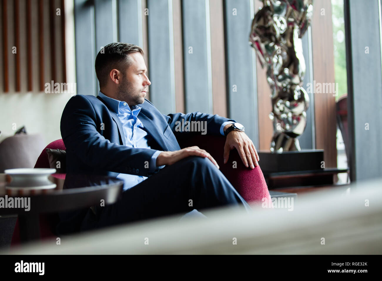Enjoy every day of your life. Positive businessman sitting on the couch while resting in the office, handsome have a break in hotel lobby. Stock Photo