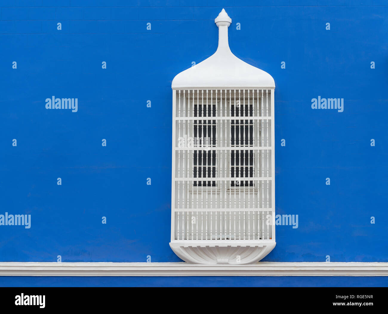 A blue wall with a lovely window with cast iron decoration and protection in the historic city center of Trujillo, Peru. Stock Photo