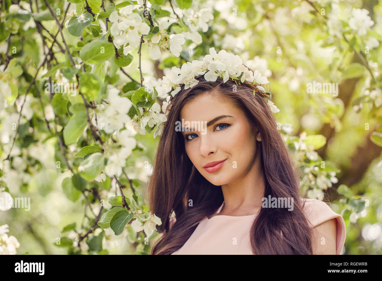 Cheerful woman face in spring flowers outdoors. Beautiful fashion model  girl with long healthy hairstyle and makeup on green leaves and apple tree  flo Stock Photo - Alamy