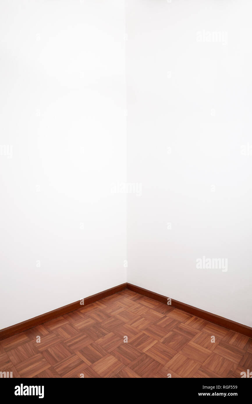 Room corner with brown wooden tiled floor and white blank wall Stock Photo