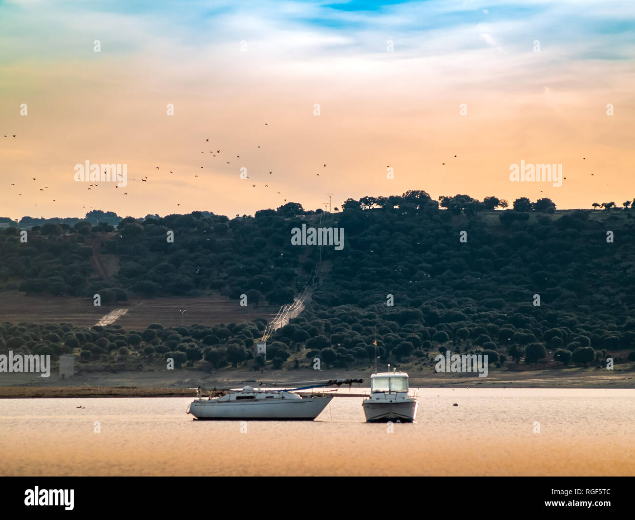 Boats on a lake at sunset, moored with a buoy and calm water in the reservoir of La Maya (Salamanca) Stock Photo