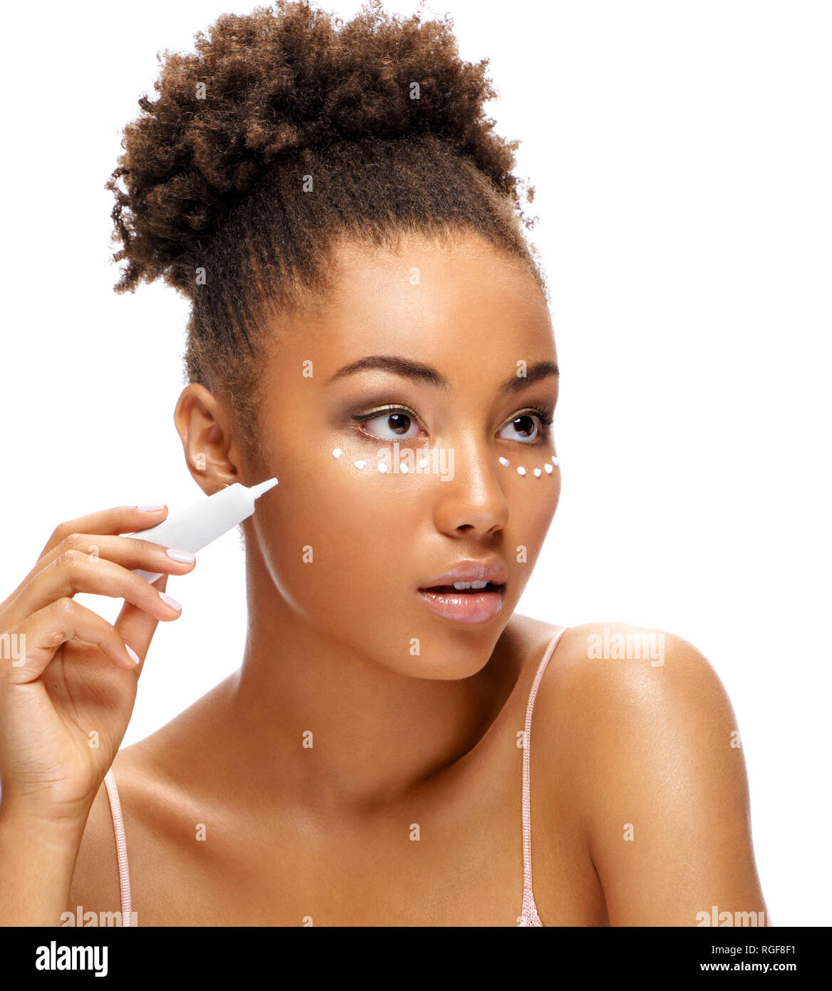 Attractive girl using cream around the eyes. Photo of african american girl with perfect skin on white background. Skin care and beauty concept Stock Photo