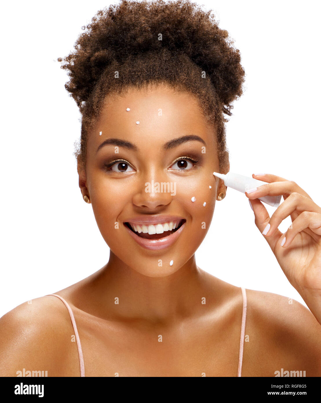 Smiling girl applying treatment cream. Photo of beautiful african american girl on white background. Skin care concept Stock Photo