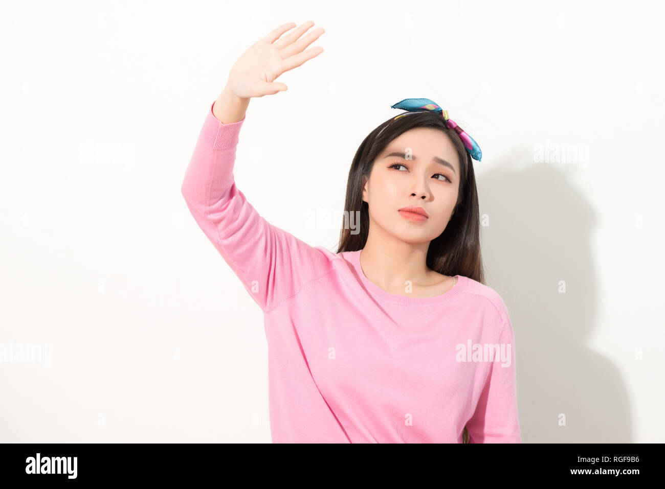 Portrait of a beautiful Asian girl covering face by hand of bright sun light. woman in a pink dress protecting her face from solar light. Skin care or Stock Photo
