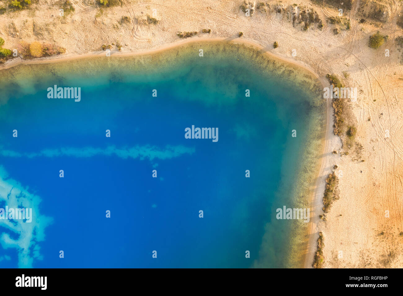 Abstract aerial image of a deep blue gravel lake in which sand is mined for the construction industry. Stock Photo