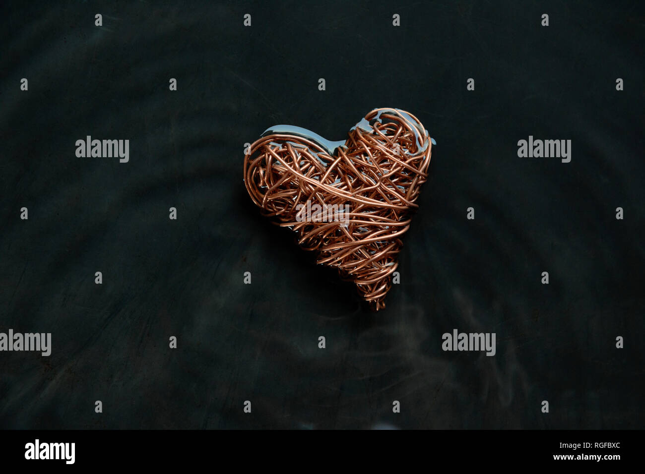 Copper wire heart made from reclaimed electric cable. Surrounding water rocked to give lines of