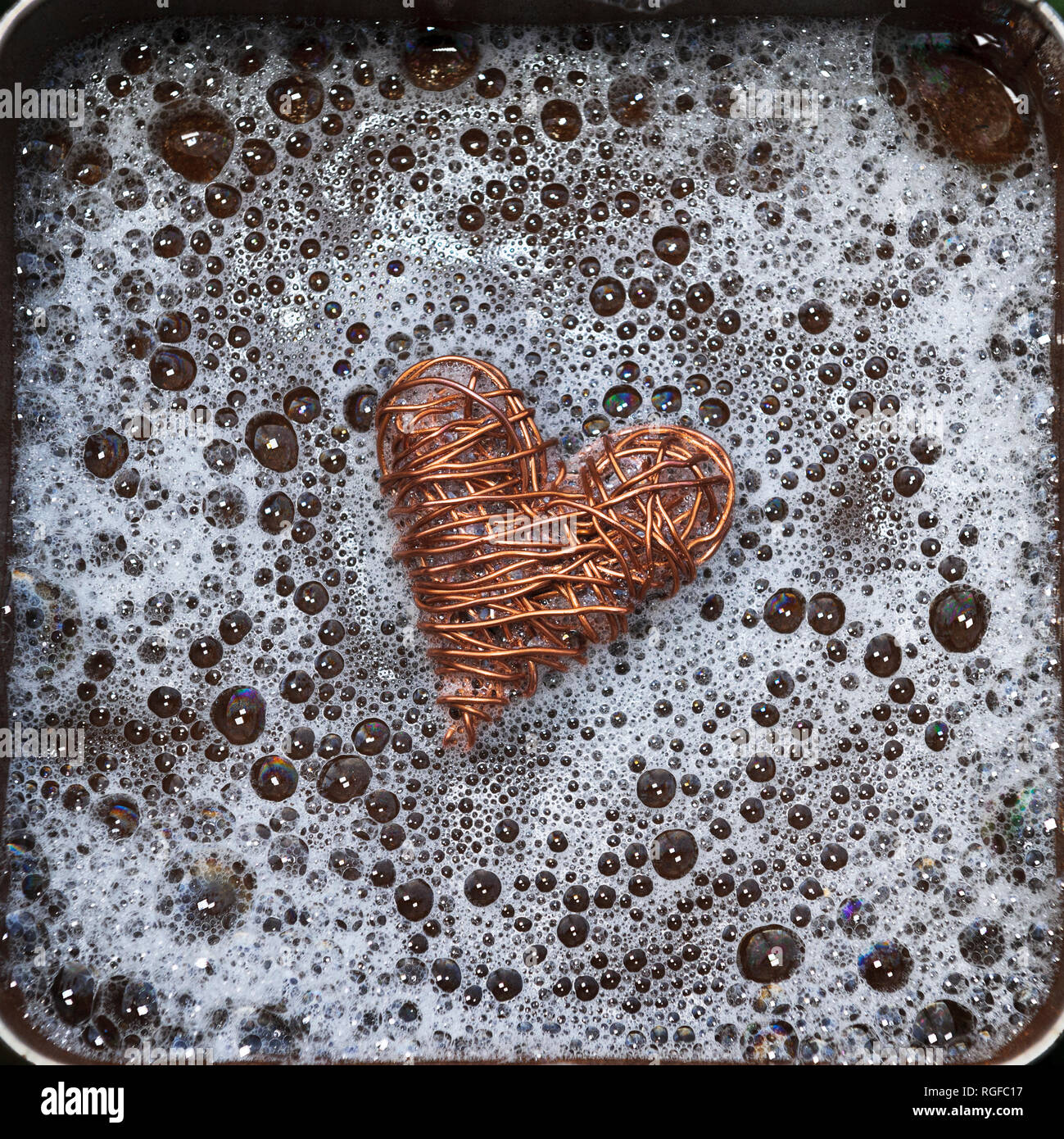 Heart made from copper wire surrounded by bubbly water. Stock Photo