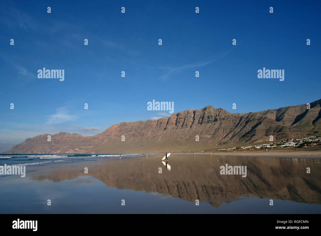 Reflection of the cliff of Famara with surfer on the Playa de Famara. Stock Photo