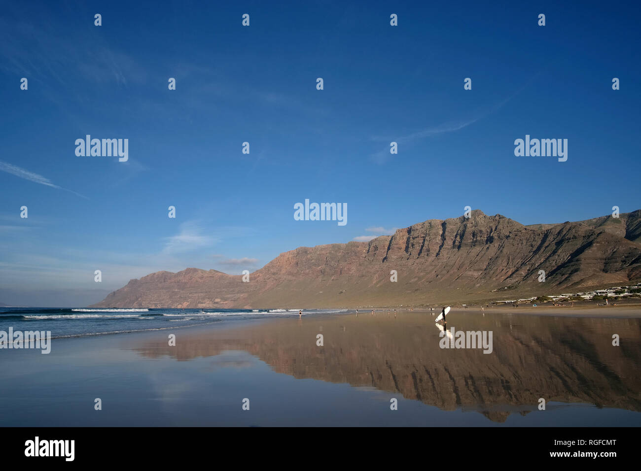 Reflection of the cliff of Famara with surfer on the Playa de Famara. Stock Photo