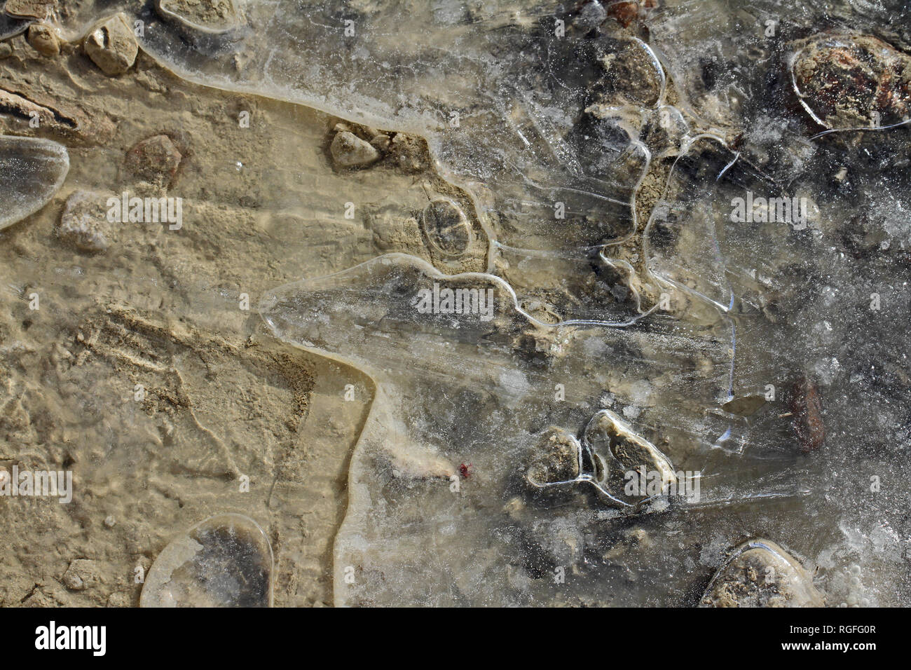 macro of an icy puddle or ice patterns on a gravel driveway in winter ...