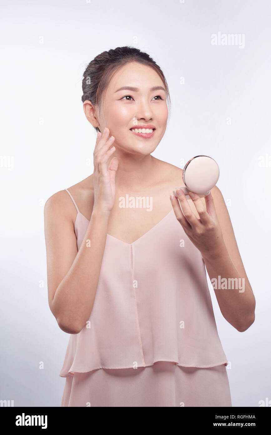 Young asian girl doing makeup, applying blusher to her cheek Stock Photo