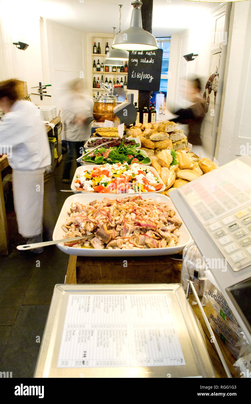 Three people working hard preparing food in Fernandez and Wells deli London. Various food including salads are being prepared for sale and ready for lunch. Stock Photo