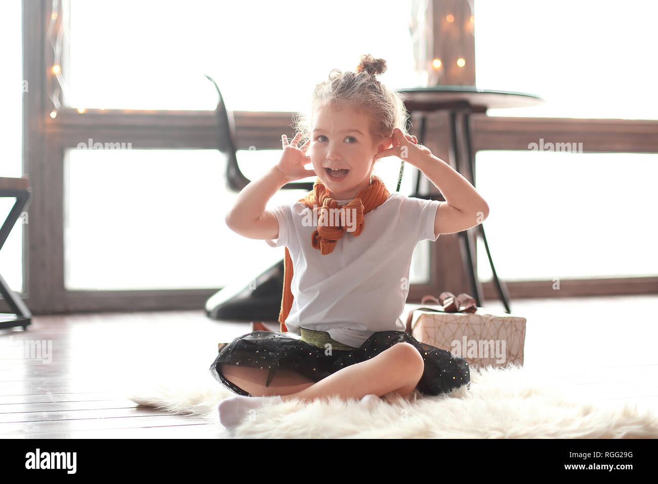 happy little girl sitting on the carpet in the living room Stock Photo ...