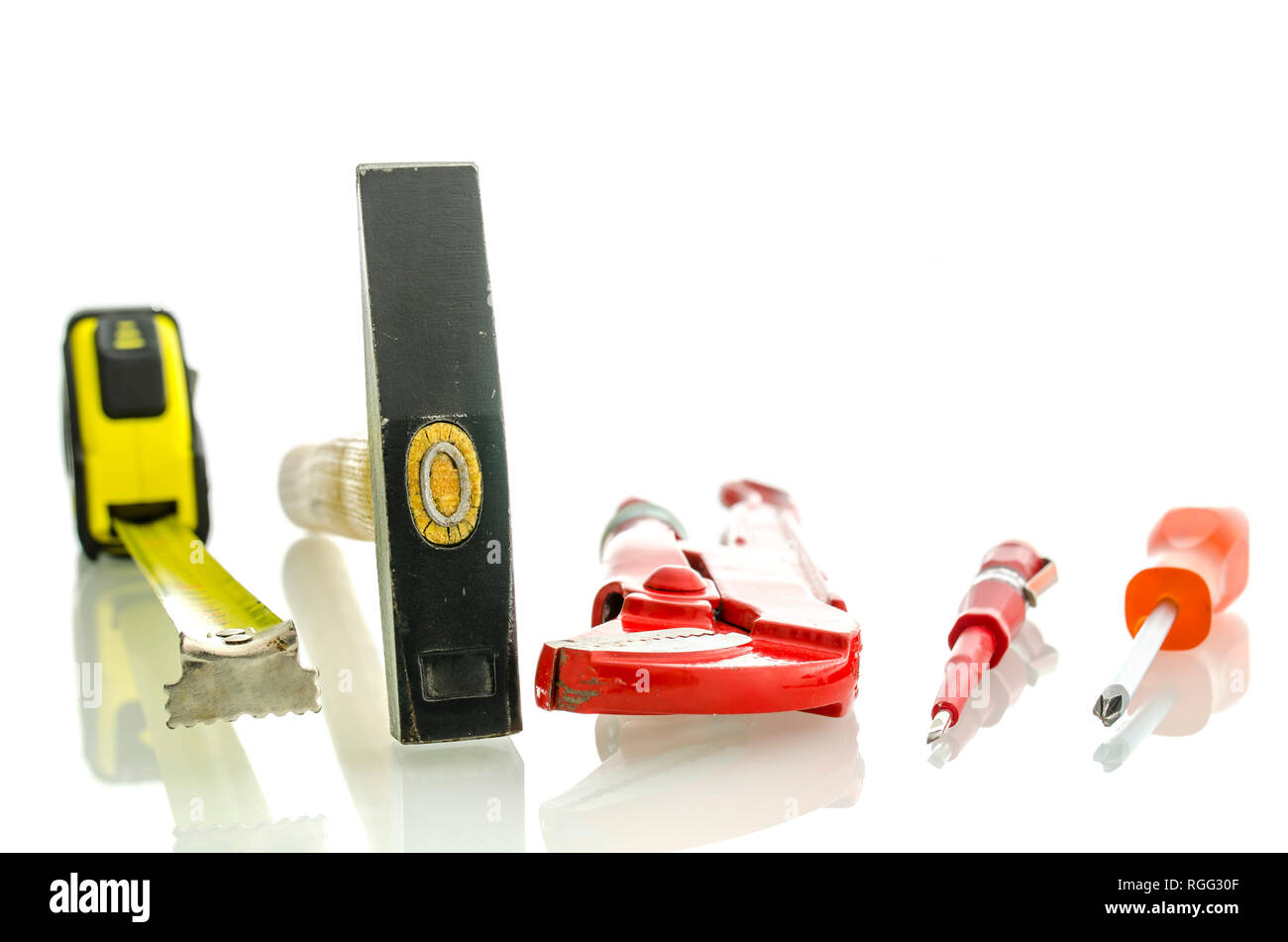 Various work tools on white desk with reflection. Isolated over white background. Stock Photo