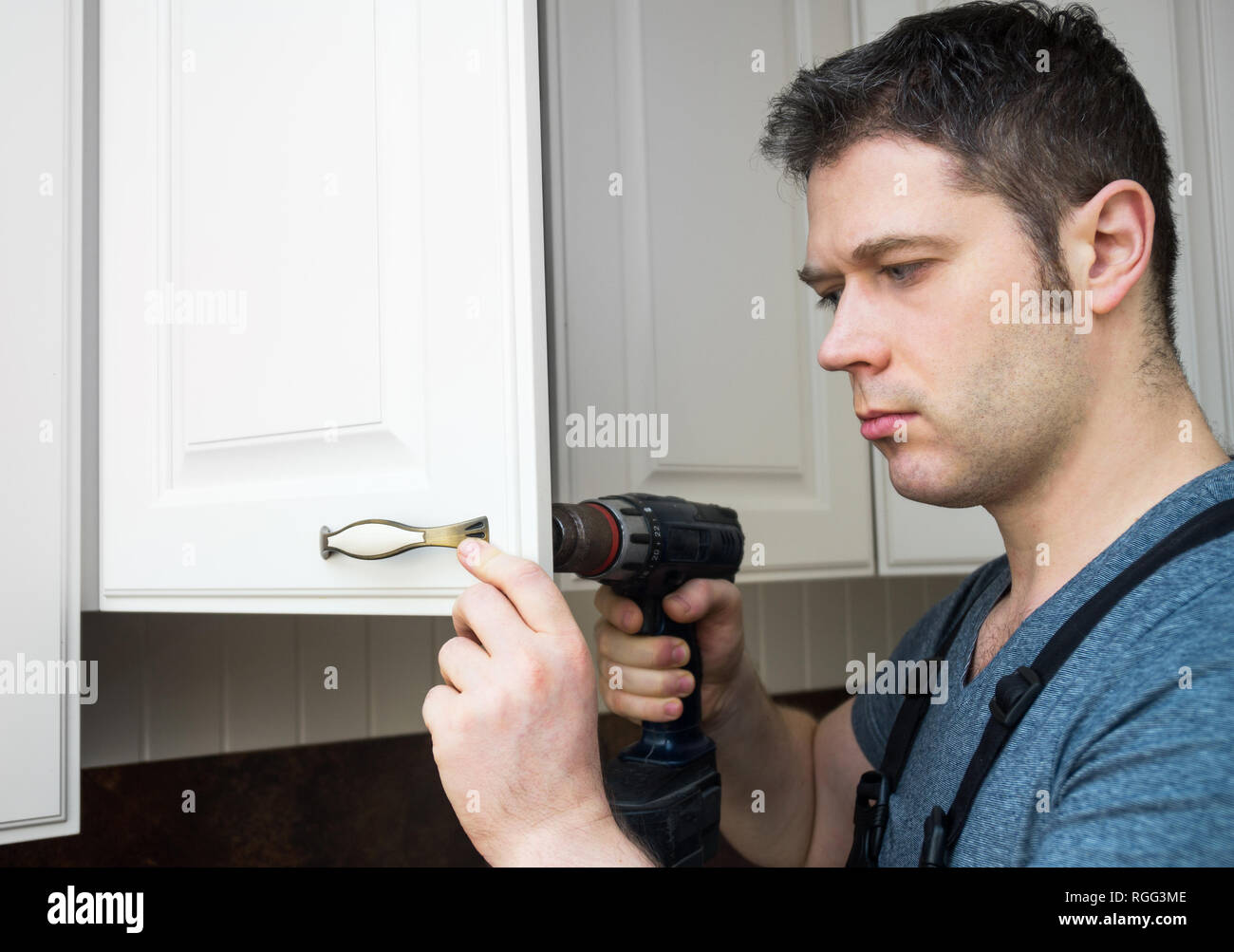 Professional handyman assembling kitchen door cabinet. Stock Photo