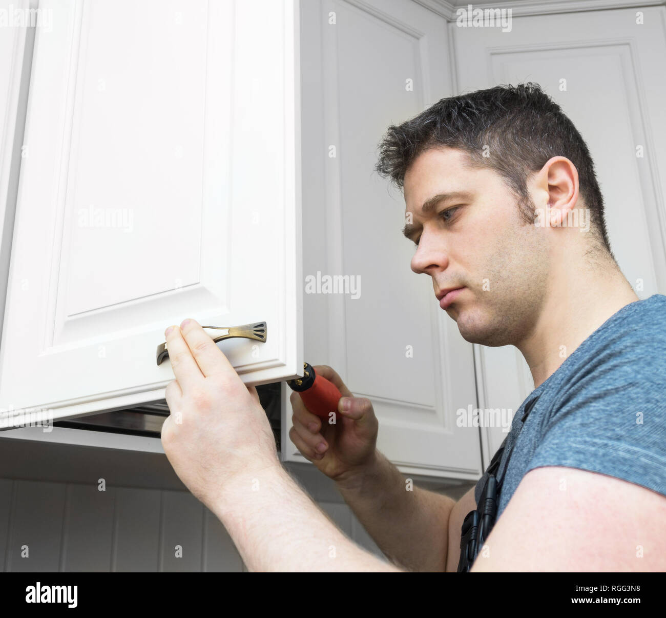 Professional handyman assembling kitchen door cabinet. Stock Photo