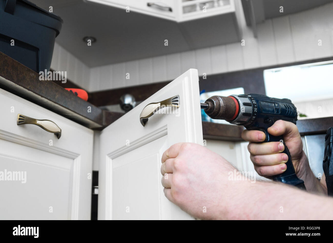 Professional handyman assembling kitchen door cabinet. Stock Photo