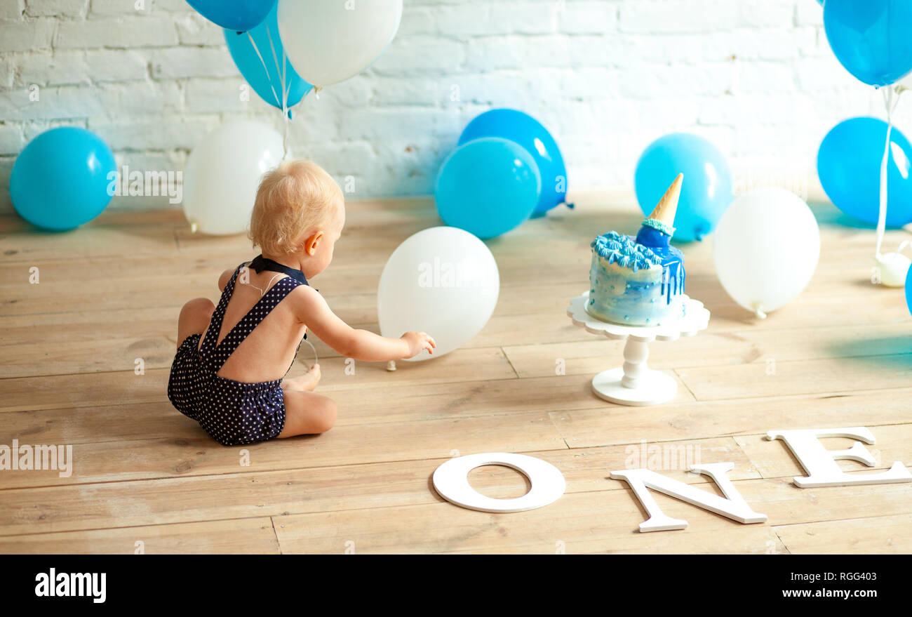 One year old boy is celebrating his first birthday among a lot of blue