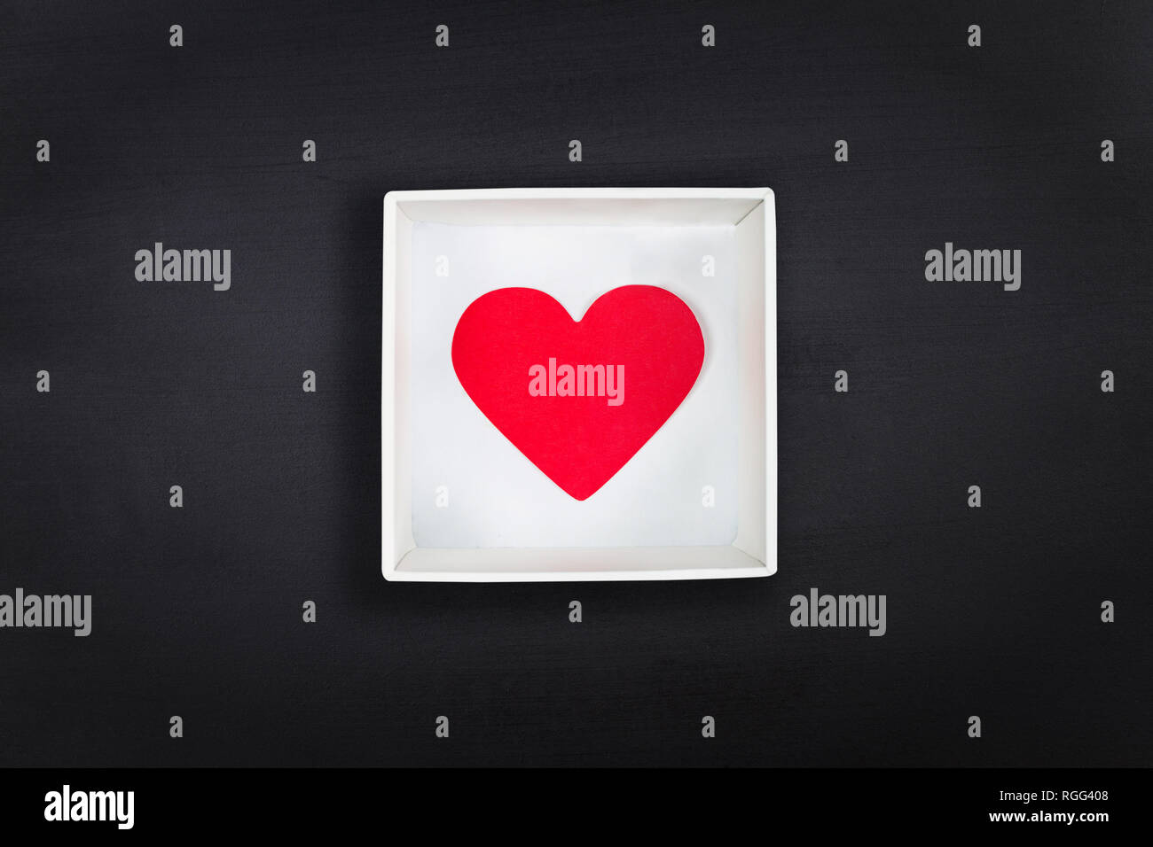 Red paper heart in white cardboard box on black chalkboard background ...
