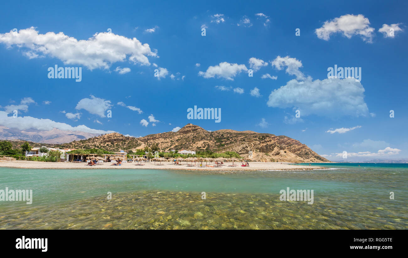 Agia Galini Beach in Crete island, Greece. Tourists relax and bath in crystal clear water of Agia Galini Beach. Stock Photo