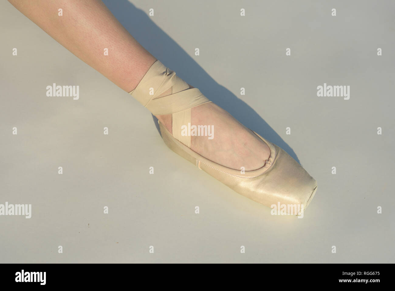 Toe dancing. Ballerina leg in white ballet shoe. Lacing ballet slipper