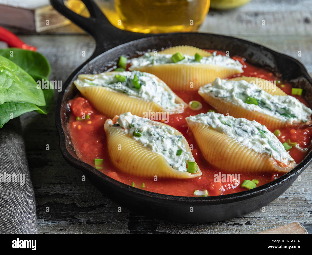 cooked pasta conchiglioni stuffed spinach and cheese, tomato sauce Stock Photo