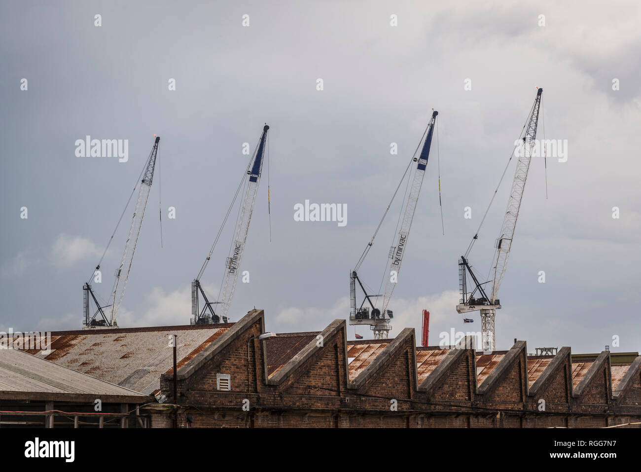 Old industrial depo building and cranes beyond it, Sydney, NSW, Australia Stock Photo
