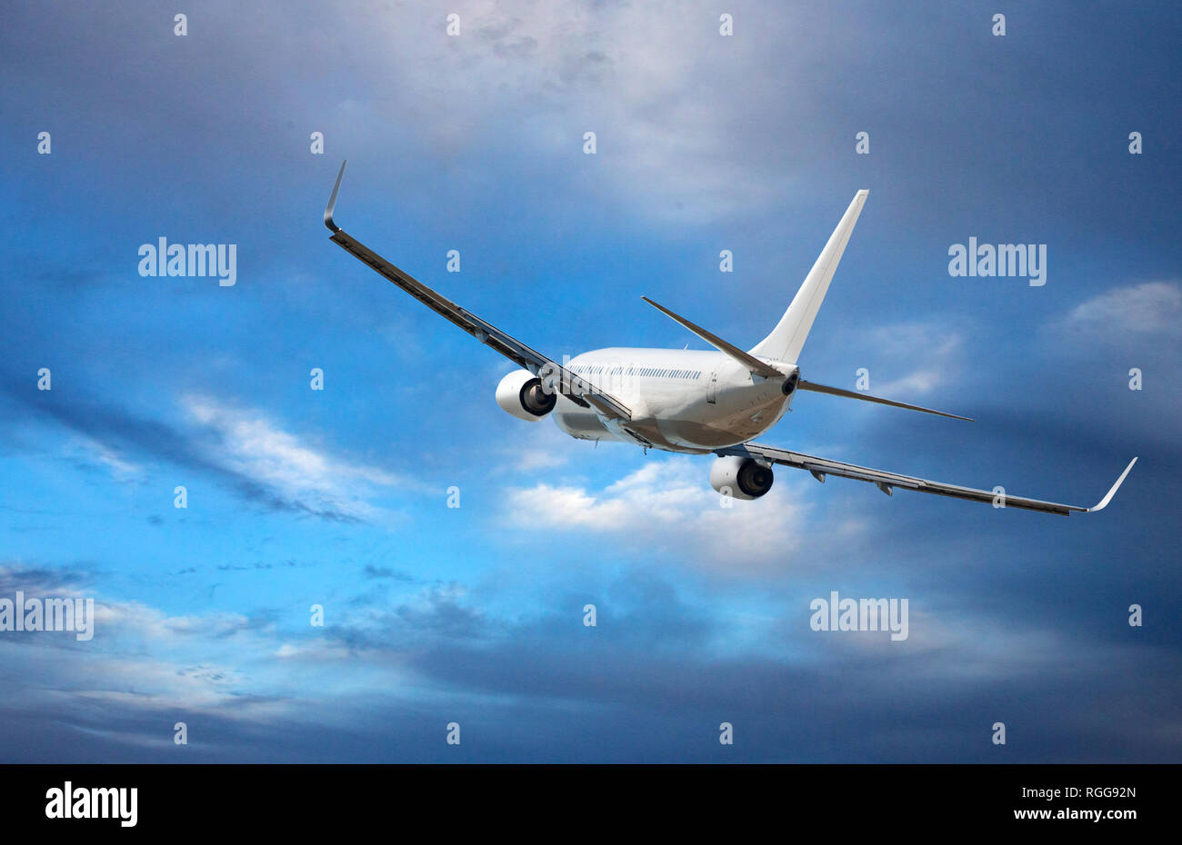 White passenger wide-body plane. Aircraft is flying in blue cloudy sky Stock Photo