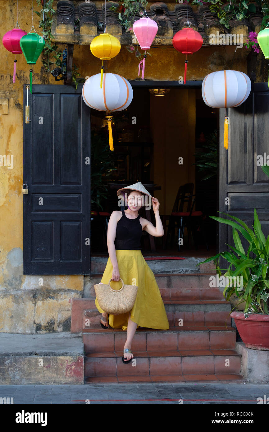 Portrait of young woman wearing a traditional vietnamese non la conical hat in old town Hoi An, Vietnam Stock Photo