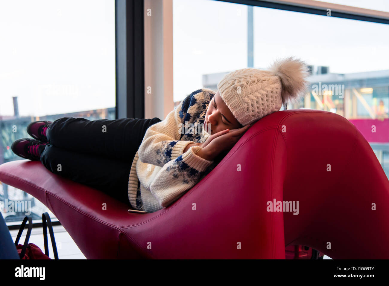 Girl taking a nap while waiting at the airport lounge Stock Photo