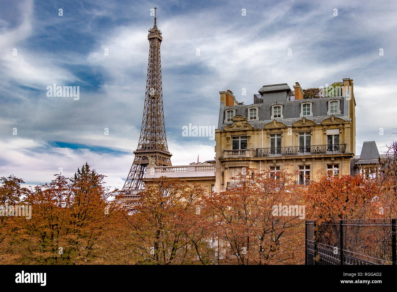 The Eiffel Tower sits behind a Grand Paris apartment building as seen from  Avenue de Camoens with the trees turning an autumnal orange colour ,Paris Stock Photo