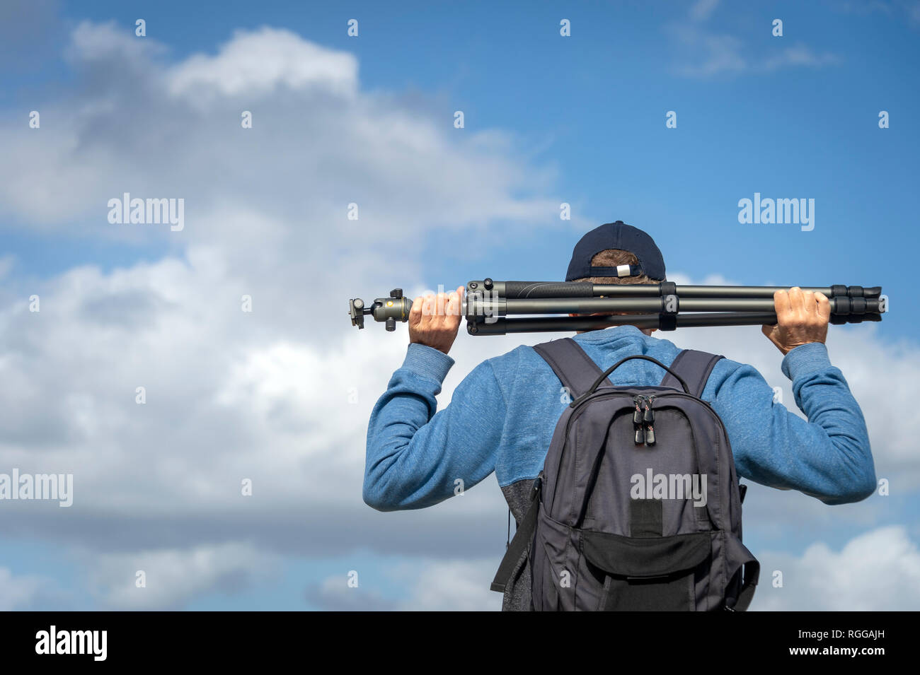 back view of a man carrying a photographic tripod and wearing a backpack Stock Photo Alamy